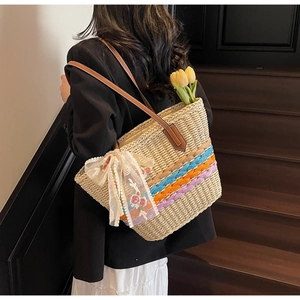 Detail of straw woven tote bag featuring colorful stripes and premium leather handles