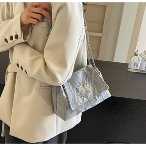 Close-up of silver crinkled texture tote bag featuring a metallic butterfly buckle detail