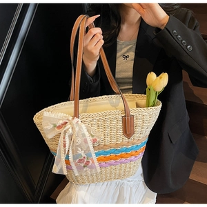 Detail of straw tote bag featuring colorful base stripes and delicate floral embroidery
