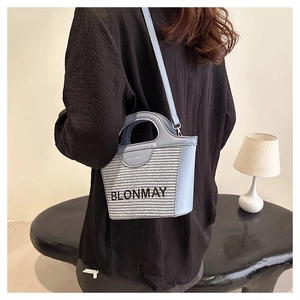 Detalle del bolso de cubo tejido azul claro con asas de cuero y logo BLONMAY en un modelo