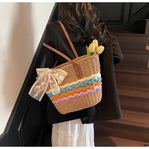 Detail of bohemian straw tote bag featuring colorful braids and floral lace ribbon