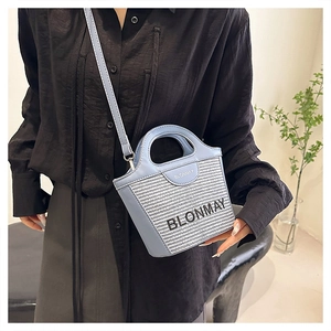 Detalle del bolso de cubo tejido azul claro en modelo para guía de tamaño y estilo