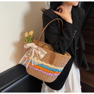 Detail of straw tote bag with colorful stripes, lace bow, and flower embroidery