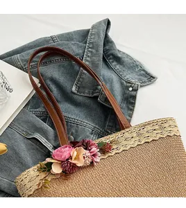 Detail of woven straw tote bag featuring floral accents and lace trim on denim backdrop