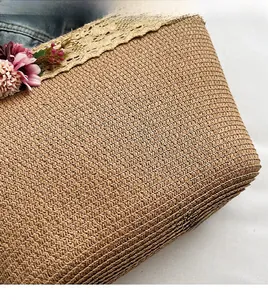 Detail of woven straw bag with beige crochet lace edge and floral embellishments