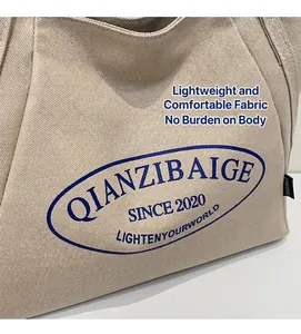 Detalle del bolso tote de lona beige que muestra la textura y el logo oval