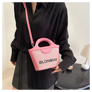 Detalle del bolso de hombro rosa en cuero trenzado con logo bordado y correa fina de piel
