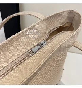 Detalle de la cremallera metálica suave en un bolso de lona beige con tejido texturizado