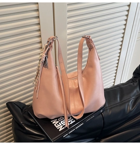 Detail of light pink hobo bag with zipper closure and woven decorative pendant