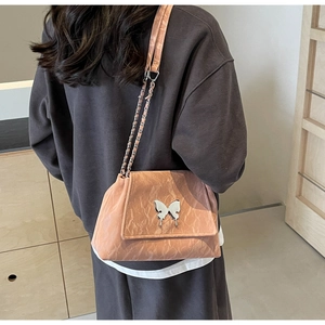 Detail of pink pleated leather tote bag with silver butterfly buckle on model's shoulder