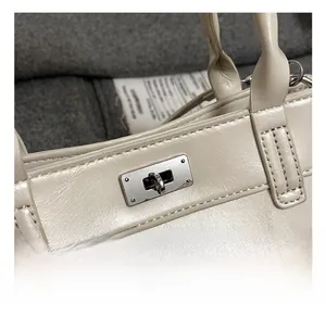 Vue rapprochée du fermoir rotatif en métal sur un sac à main en cuir blanc crème