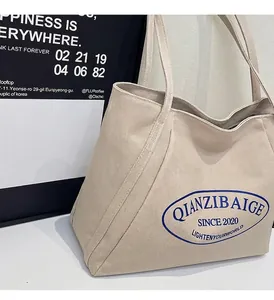 Detalle del bolso tote de lona blanco roto con estampado de letras azules vintage y textura