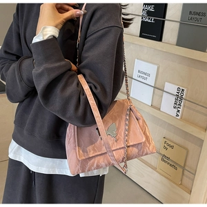 Detail of pink pleated tote bag with silver butterfly buckle and chain strap on shoulder