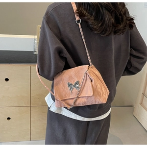 Detail of pink pleated tote bag featuring metallic butterfly buckle and silver chain strap