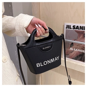 Primer plano del bolso cubo negro BLONMAY con costuras de cuero y detalles tejidos