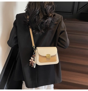 Detail of two-tone crossbody bag with gold lock, pearl chain and cute bear charm