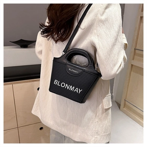 Detalle de bolso tipo cubo tejido negro con bordado BLONMAY blanco y asa de cuero