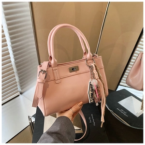 Détail d'un sac à main rose en cuir PU avec fermoir argenté et pompon tissé décoratif