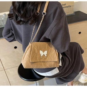 Detail of khaki tote bag with crinkled texture, silver butterfly clasp, and chain strap