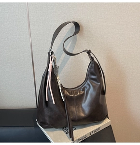 Detail of dark brown leather pleated dumpling bag with decorative woven lanyards