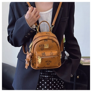 Detail of a brown leather mini backpack featuring cartoon bears and bear charm