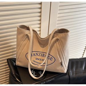 Primer plano detallado del bolso de lona beige con textura duradera y estampado azul