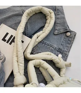 Detalle del bolso tipo cubo crema acolchado con correa larga anudada y tacto suave