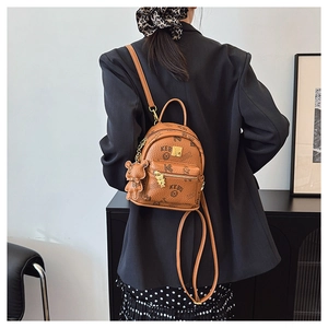 Detail of a brown leather mini backpack featuring monogram prints and a bear charm pendant