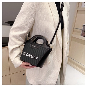 Primer plano de bolso cubo negro con textura de nervaduras y correa de hombro en modelo