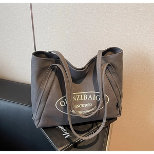 Primer plano del bolso tote de lona gris oscuro con estampado blanco y correa larga