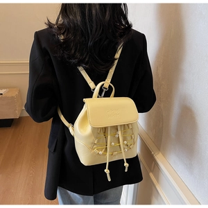 Detail of yellow mini backpack featuring pearl beads and crisscross strap design