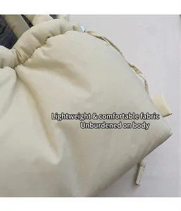 Vista de detalle del tejido acolchado crema del bolso tipo cubo con cierre de cordón