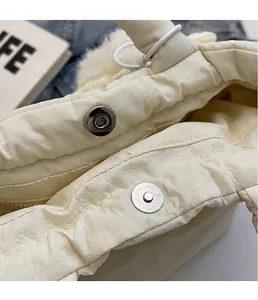 Detalle del cierre magnético metálico en un bolso cubo acolchado beige con peluche