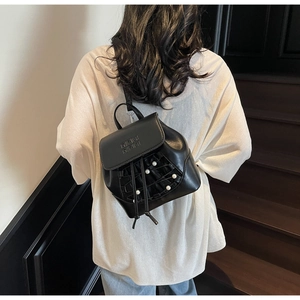 Detailed view of black mini backpack featuring pearl accents and embossed flap design