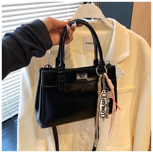 Détail du sac à main en cuir PU noir avec fermoir argenté et breloque à pompon
