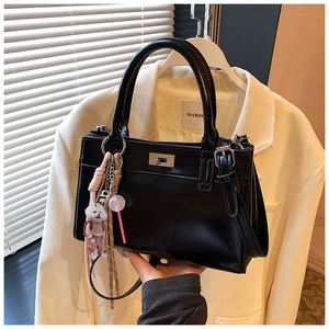 Détail du sac à main noir en similicuir avec serrure argentée et charms chiots mignons