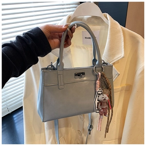 Détail du sac cabas en cuir bleu clair avec fermoir rotatif et breloque chien mignonne