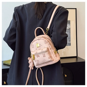 Close-up of pink mini backpack with bear prints and a plush teddy bear keychain charm