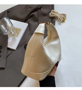 Close-up of beige moon bag showing sen&li embossed logo and premium faux leather texture