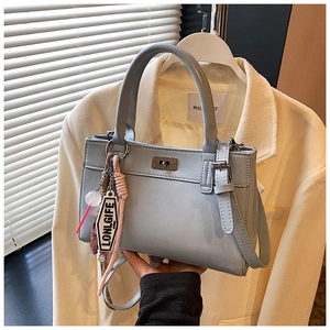 Vue détaillée du sac cabas gris-bleu avec fermoir rotatif et breloques décoratives