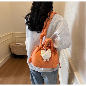 Orange quilted drawstring bucket bag with cute plush rabbit charm on a fashion model