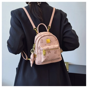 Pink mini backpack with teddy bear prints and plush charm shown on a model