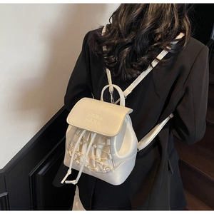 Detail of cream mini backpack featuring embossed lettering and elegant pearl drawstring accents