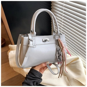 Détail du sac cabas gris clair avec fermoir rotatif en métal et breloque tissée