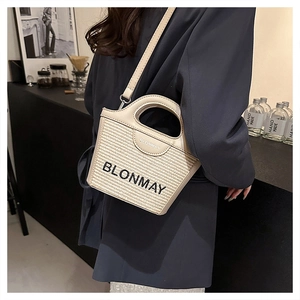 Detalle del bolso de paja BLONMAY con ribetes de cuero crema y bordado del logotipo