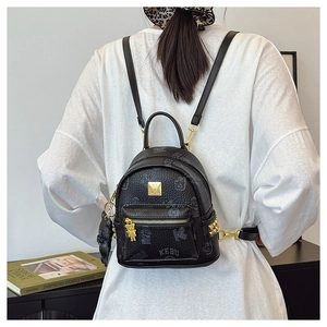 Close-up of black leather backpack with grey prints, gold rivets and a cute bear charm