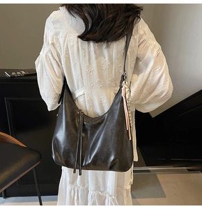 Close-up of vintage faux leather hobo bag with tassel and decorative woven rope detail