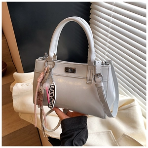 Détail du sac cabas gris avec serrure en métal, pendentif ours et bandoulière amovible