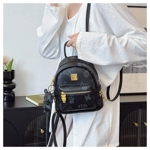 Detail of black pebbled leather mini backpack with bear prints and golden metallic hardware