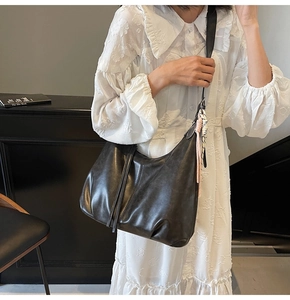 Large black slouchy hobo bag with striped scarf detail worn with a white lace dress